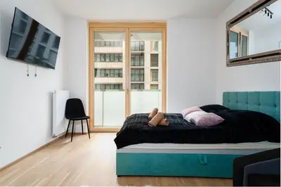 a bedroom with a bed with a blue headboard and a window at Big Central Living in Prague