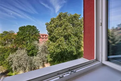 a window with a view of trees and a building at Apartmány Ubytování Alfa in Prague