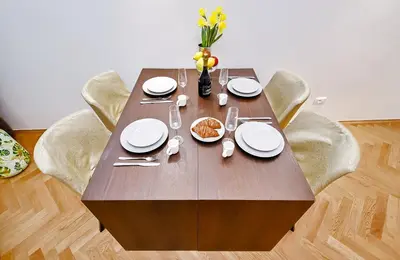 a wooden table with chairs and plates and a vase of flowers at Kora Premiere Collection in Prague