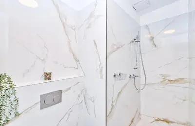 a white bathroom with a shower with marble walls at Kora Premiere Collection in Prague