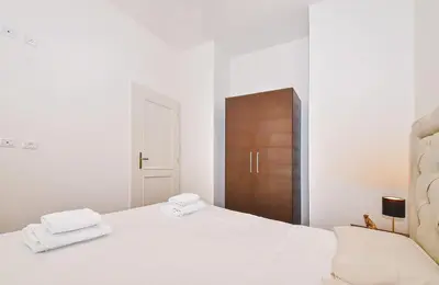a white bedroom with a bed and a wooden cabinet at Kora Premiere Collection in Prague