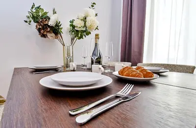 a wooden table with white plates and napkins and flowers at Kora Premiere Collection in Prague