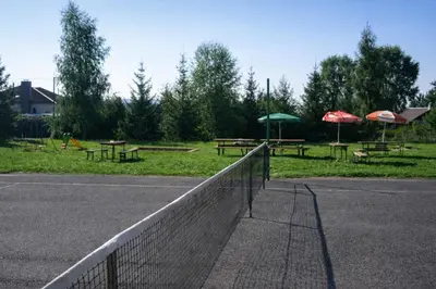a tennis court with picnic tables and umbrellas at Autocamp Kosmonosy in Mladá Boleslav