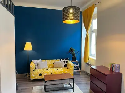 a living room with a yellow couch and a blue wall at Loft in the heart of Anděl in Prague