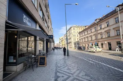 a person walking down a street next to a store at Cozy Apartment in the heart of Prague in Prague