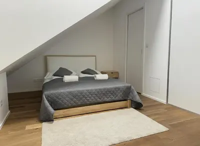 a white bedroom with a bed and a staircase at Bright Apartment near Main Station in Prague