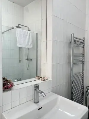 a white bathroom with a sink and a mirror at Bright Apartment near Main Station in Prague