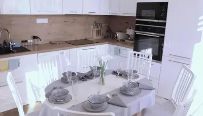 a white kitchen with a table with white chairs at Bright Apartment near Main Station in Prague