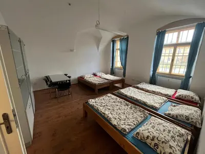 a room with three beds and a table in it at Artillery Barracks Accommodation in Terezín