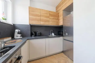 a kitchen with white cabinets and wood accents at Sky Apartment Residence in Prague