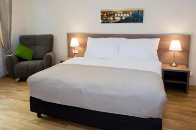 a bedroom with a large bed and a chair at Limes Apartments in Prague