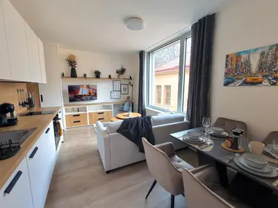 a kitchen and living room with a table and a couch at Bright Modern 1BR • Quiet • 20 min Center • Grill in Prague
