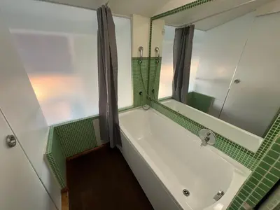 a bathroom with a bath tub with a mirror at Opatovicka Central Living in Prague