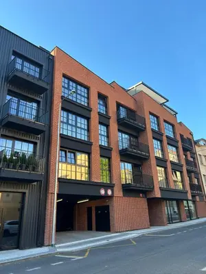 a red brick building with balconies on a street at PRAHA 5, apartmán PECHLÁTOVA - BAZÉN, PARKOVÁNÍ V DOMĚ in Golčŭv Jeníkov