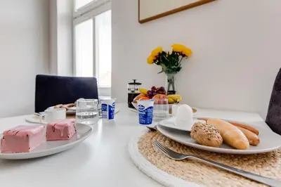a table with two plates of pastries and a vase of flowers at Comfy Apartment with Bedroom Nook in Prague