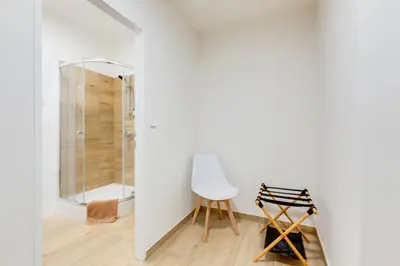 a white bathroom with a shower and a white chair at Comfy Apartment with Bedroom Nook in Prague