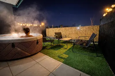 a man in a hot tub on a patio at night at Stylish Studio with Private Hot Tub & Terrace in Prague