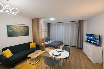 a living room with a green couch and a bed at Stylish Studio with Private Hot Tub & Terrace in Prague