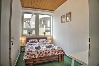 a bedroom with a bed with a floral comforter and a window at Station Stay Rooms near Main Train Station in Prague