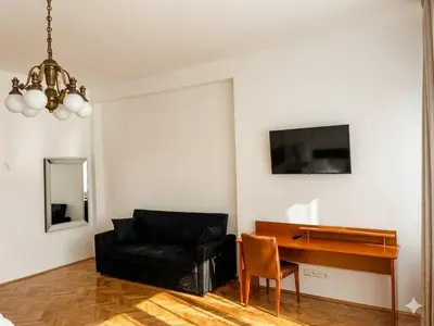 a living room with a black couch and a desk at Pawlovnia Hotel in Prague