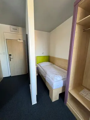 a small room with a bed and a closet at Sport hotel Sletiště in Kladno