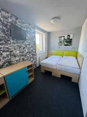 a bedroom with a bed and a desk and a tv at Sport hotel Sletiště in Kladno