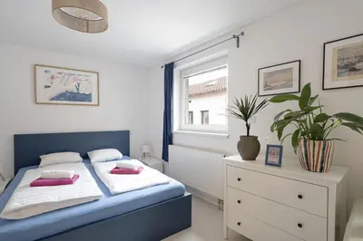 a bedroom with a blue and white bed and a window at Tichý byt blízko Pražského hradu in Prague