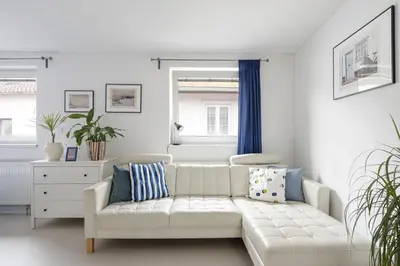 a living room with a white couch and blue curtains at Tichý byt blízko Pražského hradu in Prague
