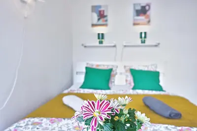 a bedroom with a bed with green pillows and flowers on it at Prague Family Guest House - Rooms with shared bathroom in Prague