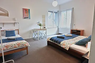 a bedroom with two beds and a desk and a window at Prague Family Guest House - Rooms with shared bathroom in Prague