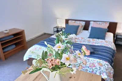 a room with a bed with a table with flowers on it at Prague Family Guest House - Rooms with shared bathroom in Prague