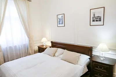a bedroom with a bed with two lamps and a window at White & Gray Apartments in Prague