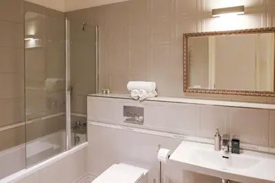 a bathroom with a sink and a shower and a mirror at White & Gray Apartments in Prague