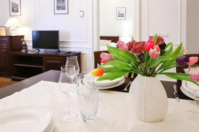 a vase of flowers sitting on a table with wine glasses at White & Gray Apartments in Prague