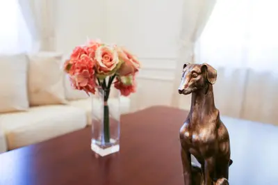 a statue of a dog on a table next to a vase of flowers at White & Gray Apartments in Prague