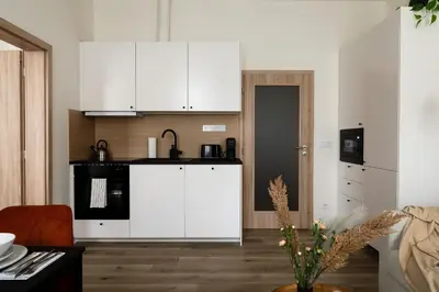 a kitchen with white cabinets and a black counter at U Zvonu Deluxe Apartments with Self Check-in in Prague