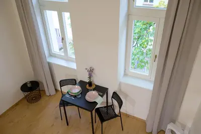 a table and chairs in a room with two windows at Modern New Town Studio Heart of the City in Prague