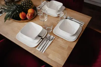 a table with white plates and glasses and a bowl of fruit at COZY&DELUX Family apartment 3 min from Metro in Prague