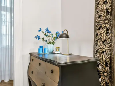 a dresser with a lamp and a vase with blue flowers at Design Spacy Apartman by City Center in Prague