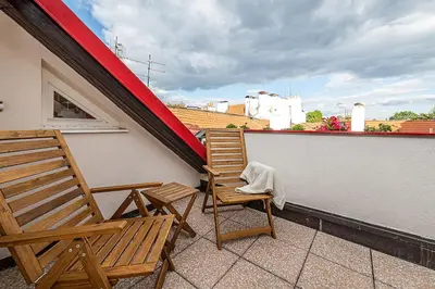 two wooden chairs sitting on a balcony with a roof at Picturesque Apt in Lesser Town with lovely Terrace in Prague