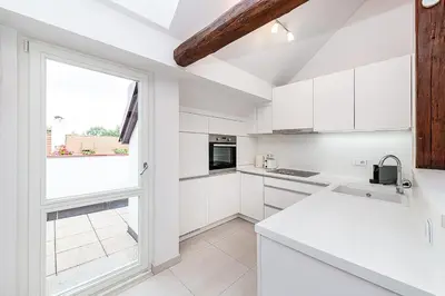 a kitchen with white cabinets and a large window at Picturesque Apt in Lesser Town with lovely Terrace in Prague