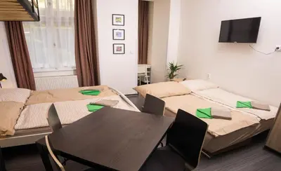 a room with two beds and a table and a tv at Flying Bed Apartment close to Prague Castle and Airport in Prague