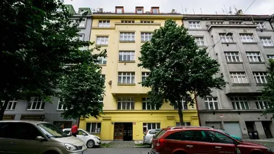 a yellow building with cars parked in front of it at Flying Bed Apartment close to Prague Castle and Airport in Prague