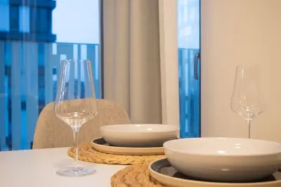 a table with two wine glasses and bowls on it at Panorama Apartment with Parking in Prague