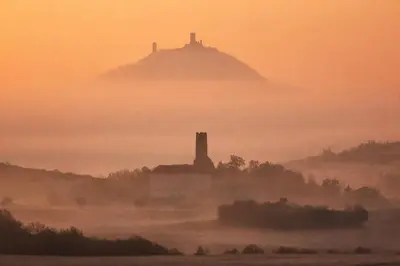 a foggy field with a hill in the distance with a building in the foreground at Kovárna Klapý pod Hazmburkem - České středohoří in Klapý