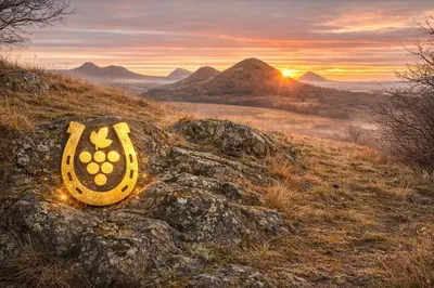 a rock on a hill with the sunset in the background at Kovárna Klapý pod Hazmburkem - České středohoří in Klapý