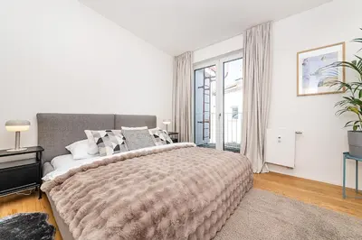 a white bedroom with a large bed and a window at Rooftop APT with beautiful view and free parking in Prague
