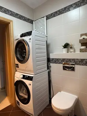a washer and dryer in a bathroom with a toilet at Easy City Access Bright 1BR with Underground Parking in Prague