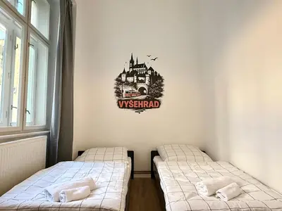 two beds in a room with a castle on the wall at MiSTO 16 in Prague