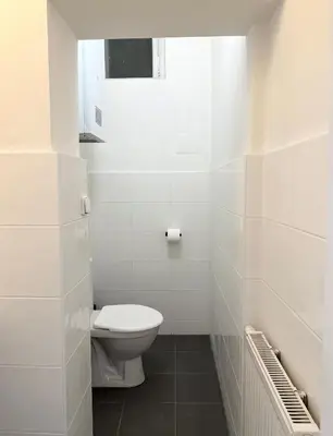 a white bathroom with a toilet and a window at MiSTO 16 in Prague
